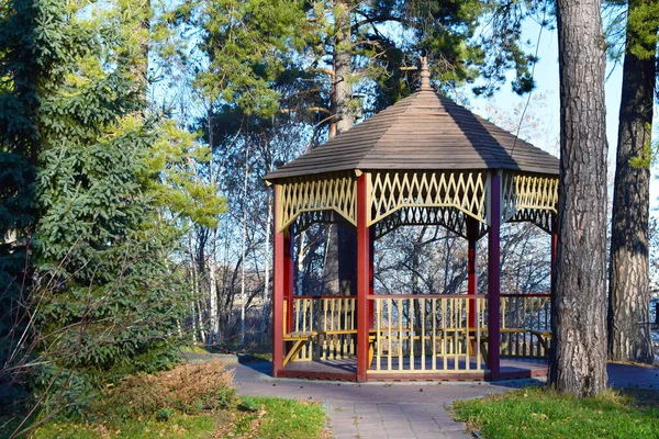 A wooden arbor with a pattern stands in the middle of trees — Stock Photo, Image