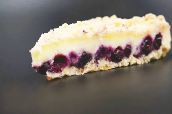 Stuk taart met paarse bessen in een wit koekje. — Stockfoto