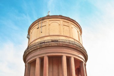 yellow water tower with columns against a blue sky