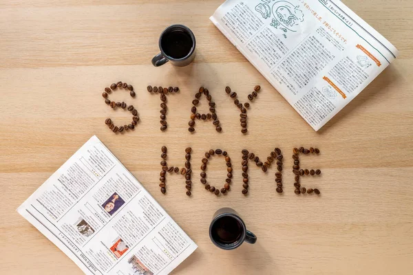 Inscription stay home with coffee beans with cup of coffee and japanese newspapers
