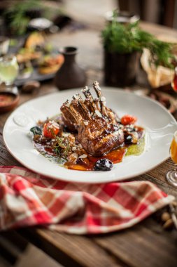 Izgara pirzola, sos, ahşap masa, güneşli gün ışığı restoranı.