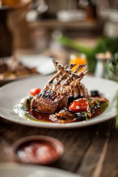 Izgara pirzola, sos, ahşap masa, güneşli gün ışığı restoranı.