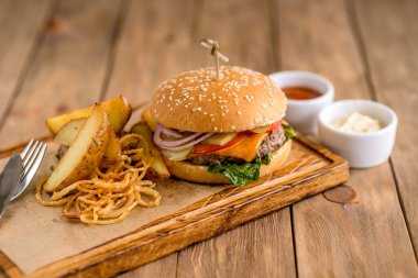 Biftek peynirli burger fesleğen soğan soslu patates ızgara soğan kağıt tahta tahta tahta tahta tahta tahta tahta tahta ahşap kafe teras bokeh