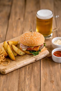 Biftek peynirli burger fesleğen soğan soslu patates ızgara soğan birası kağıt tahta tahta tahta tahta tahta tahta tahta tahta tahta ahşap kafe restoran terası bokeh
