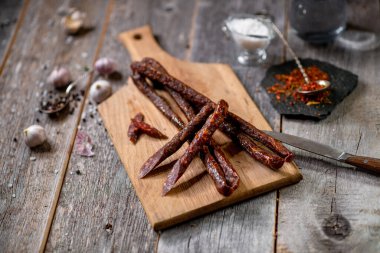 Ahşap tahtada salam ve sarımsaklı baharat kaşığı bıçağı.