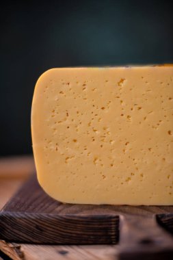 Orta sert peynir gouda edam tahtanın üzerinde güneş ışığı masasının üzerinde geleneksel masa dokusu manzarası