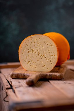 Orta sert peynir gouda edam tahtanın üzerinde güneş ışığı masasının üzerinde geleneksel masa dokusu manzarası