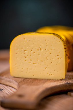 Orta sert peynir gouda edam tahtanın üzerinde güneş ışığı masasının üzerinde geleneksel masa dokusu manzarası