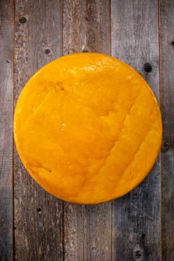 Orta boy sert peynirli Edam gouda parmesan peyniri. Tahtada parmesan renginde. Bıçak ahşap desenli.