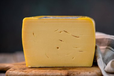 Orta boy sert peynirli Edam gouda parmesan peyniri. Tahtada parmesan renginde. Bıçak ahşap desenli.