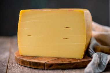 Orta boy sert peynirli Edam gouda parmesan peyniri. Tahtada parmesan renginde. Bıçak ahşap desenli.