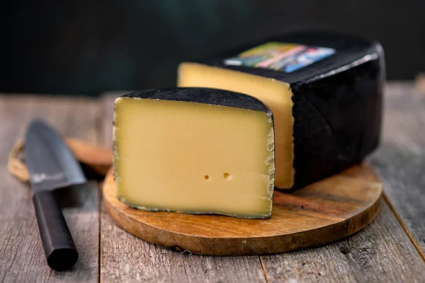 Orta boy sert peynirli gouda edam, tahta tahtada. Bıçak ahşap desenli, gündüz görüşlü.
