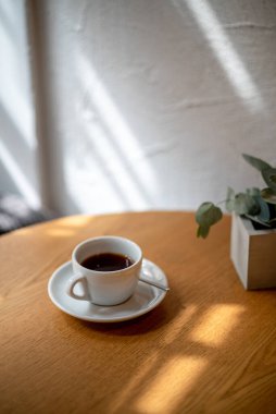 Kahvehanenin masasında bir fincan siyah filtre kahve. Gün ışığı manzaralı kahve.