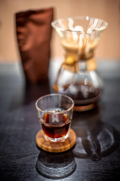 ケメックスフィルター付きブラックコーヒー醸造は ガラスハウスカフェの日光テーブルサイドビューに注ぎます — ストック写真