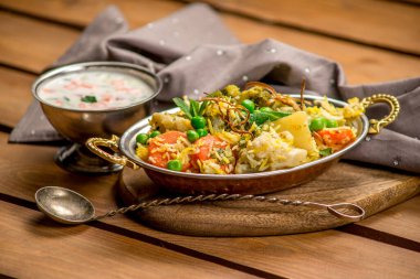 Biryani Hint mutfağı sebzeli pirinç geleneksel ahşap tahta desenli.