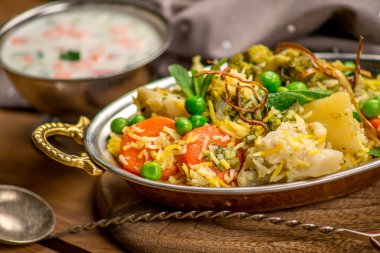 Biryani Hint mutfağı sebzeli pirinç geleneksel ahşap tahta desenli.