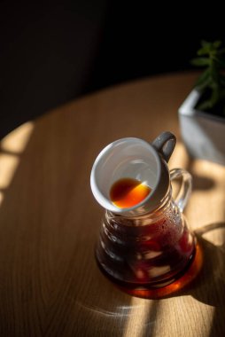 Kahve servisindeki masaya koyu filtre kahve. Sert kahve fincanın yanına dökülüyor.