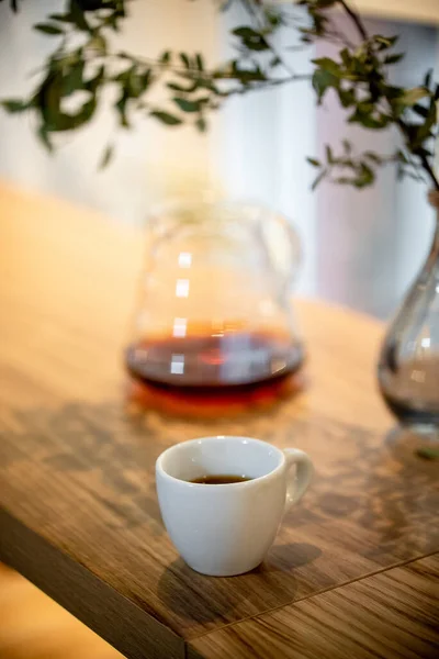 カフェサービスのテーブルの上の黒いフィルターコーヒーケトルハリオはカップサイドビューに注ぐ — ストック写真