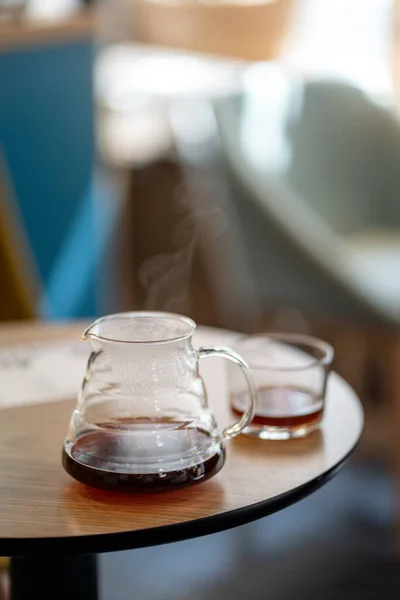 カフェサービスのテーブルの上の黒いフィルターコーヒーケトルハリオはカップサイドビューに注ぐ — ストック写真
