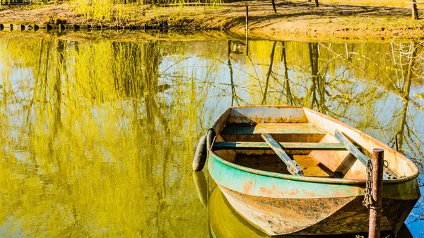 Small boat anchored on the shore in a lake in a park — Stock Photo, Image