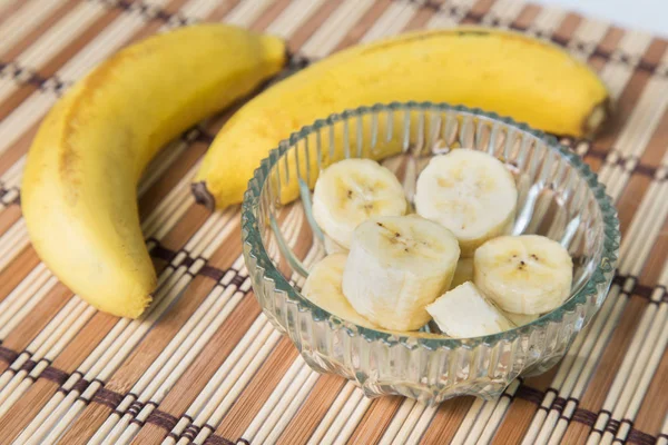 Un banc de bananes et une banane tranchée dans un pot sur un fond de bois . — Photo