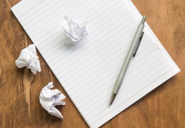 Beyaz kağıt ve kalem ile defter ahşap masanın üstüne çökmek.