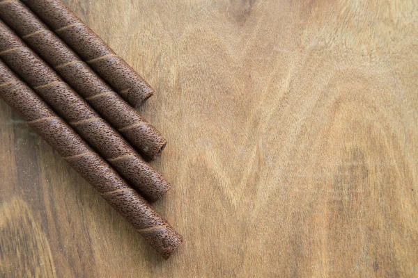 Rolos de wafer com chocolate na mesa de madeira . — Fotografia de Stock