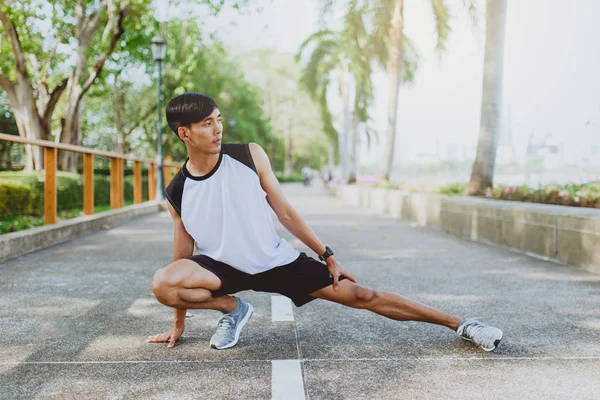 Jeune homme étirant les corps, se réchauffant pour le jogging dans le parc public . — Photo