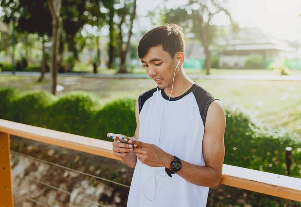 Oynama ve genel Park'ta smartphone üzerinden müzik çekici genç sporcu.