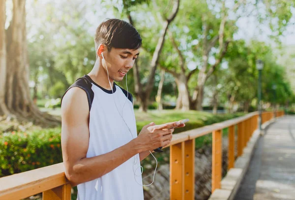 Oynama ve genel Park'ta smartphone üzerinden müzik çekici genç sporcu.