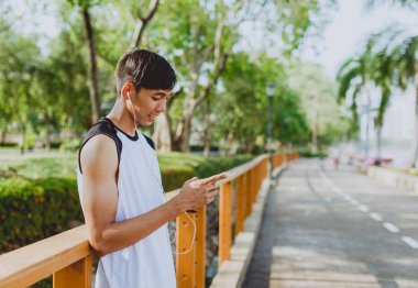 Oynama ve genel Park'ta smartphone üzerinden müzik çekici genç sporcu.