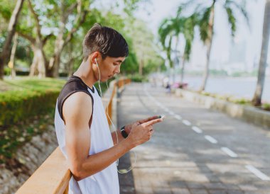 Oynama ve genel Park'ta smartphone üzerinden müzik çekici genç sporcu.