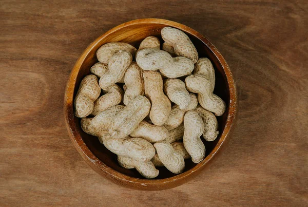 Peanuts in shell in a wooden bowl, selective focus (vintage filter).