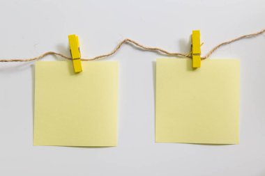 Boş not kağıdı ile beyaz arka plan üzerinde asılı clothespin.