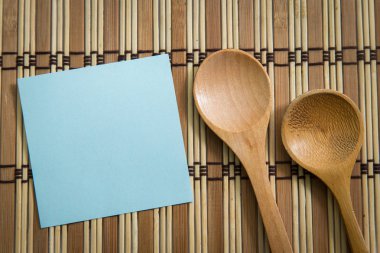 Ahşap zemin, yemek kavramı üzerine tahta kaşıkla boş not kağıdı.