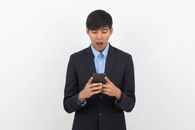 Beyaz arka planda izole edilmiş şaşırtıcı yüzüyle akıllı telefon çalan Asyalı genç iş adamı..