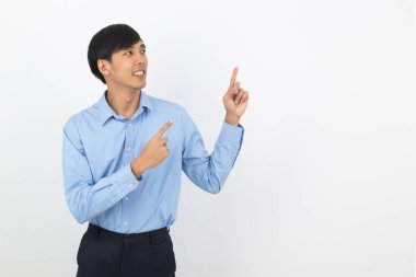 Mavi gömlekli genç Asyalı iş adamı beyaz arka planda sırıtırken bir yandan ürünü ya da fikri sunmak için parmağıyla kenarı işaret ediyor..