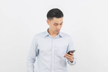 Genç Asyalı yakışıklı iş adamı akıllı telefon oynuyor ve beyaz arka planda izole edilmiş olarak düşünüyor..
