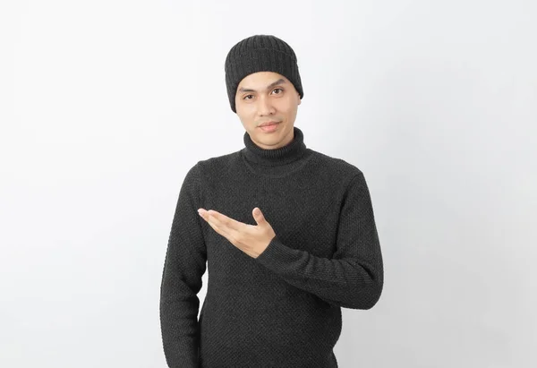 年轻英俊的亚洲男子 身穿灰色毛衣 头戴贝尼帽 手拿着手指尖 展示一种产品或一种白色背景的想法 — 图库照片