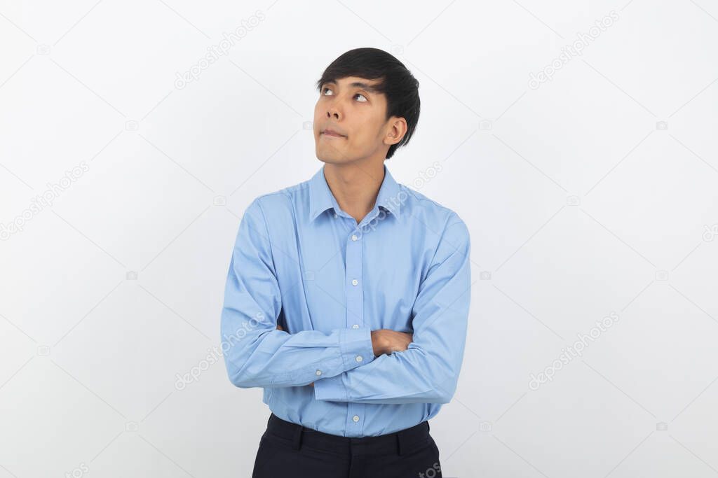 Young handsome asian man thinking an idea while looking up with arms crossed isolated on white background.