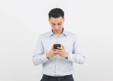 Genç Asyalı yakışıklı iş adamı beyaz arka planda sırıtarak akıllı telefon oynuyor..