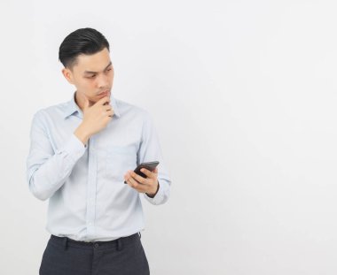 Genç Asyalı yakışıklı iş adamı akıllı telefon oynuyor ve beyaz arka planda izole edilmiş olarak düşünüyor..