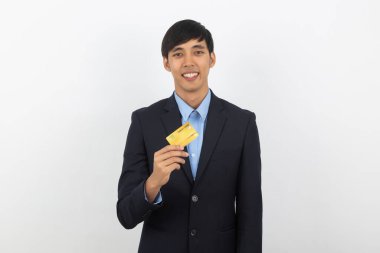 Genç yakışıklı Asyalı iş adamı kredi kartı tutuyor ve beyaz arka planda izole edilmiş kameraya bakıyor..