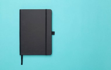 Siyah defter mavi arka planda izole edilmiş. Kopyalama alanı ile düz ya da Üst görünüm açısı.