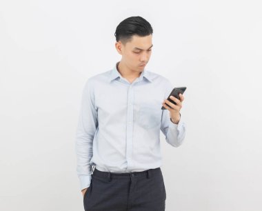 Genç Asyalı yakışıklı iş adamı akıllı telefon oynuyor ve beyaz arka planda izole edilmiş olarak düşünüyor..