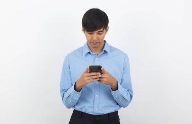 Genç Asyalı yakışıklı iş adamı beyaz arka planda sırıtarak akıllı telefon oynuyor..