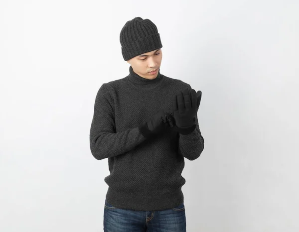 年轻英俊的亚裔男子 身穿灰色毛衣 头戴贝尼帽 白底望着她温暖的手套 — 图库照片