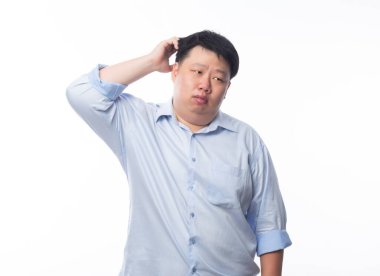 Mavi gömlekli Asyalı Şişman Adam beyaz arka planda şüpheli bir yüz ifadesiyle kopyalama alanı arıyor.