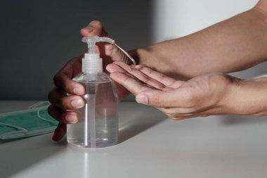 Enfeksiyonu önlemek için alkol dezenfektanı jeli pompası ve tıbbi maske kullanan eller, Covid-19 veya Corona virüsü, Coronavirus önleme.