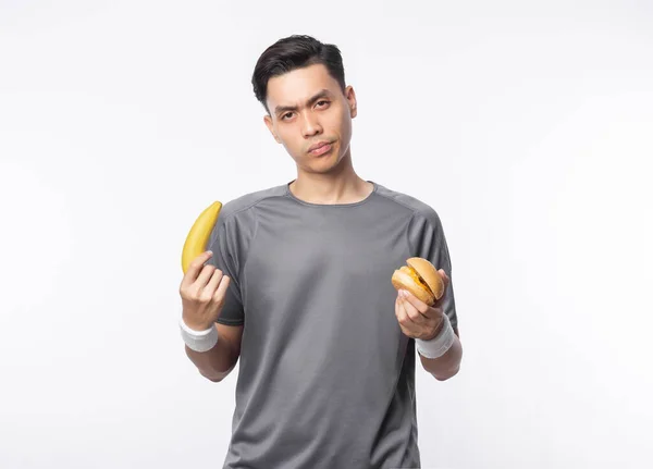 아시아 남자가 배경에 스러운 얼굴로 바나나 햄버거 — 스톡 사진